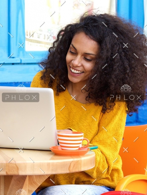 demo-attachment-65-happy-young-woman-sitting-at-outdoor-cafe-using-PFFBJ93